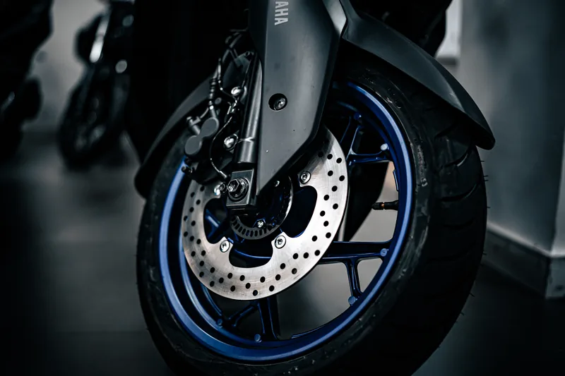 Roda dianteira da XMAX com aro azul e disco de freio.